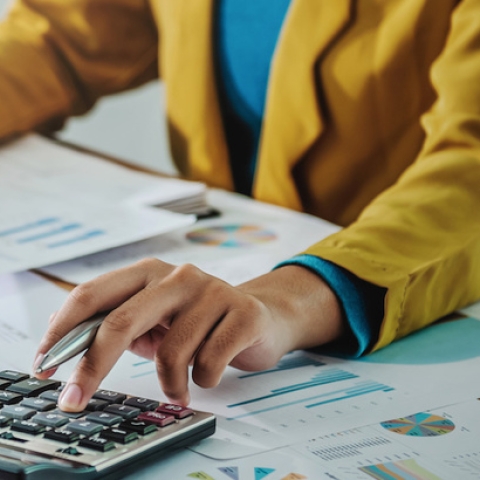 hands holding sheet with graph and typing on calculator