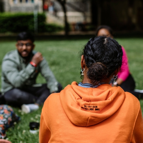 Three students sat down on grassy field 