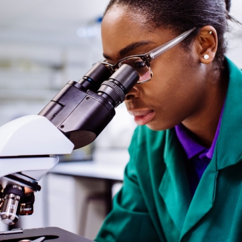 Researcher looking down microscope 