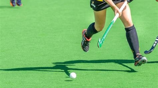 lower half of person running with hockey stick and ball
