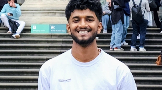 Man smiling looking at camera in forefront background has group of people not looking at camera