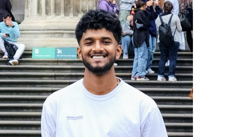 Man smiling looking at camera in forefront background has group of people not looking at camera