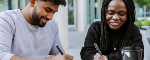 Two students working together from the same book in Eldon seating area