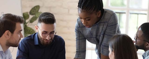 girl standing helping a group of 2 with paperwork