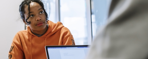 girl looking at someone with laptop