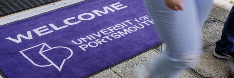 Two students cross the welcome mat and enter lobby of Technology Facilities
