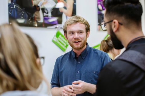 member of staff talking to two people at volunteering fair